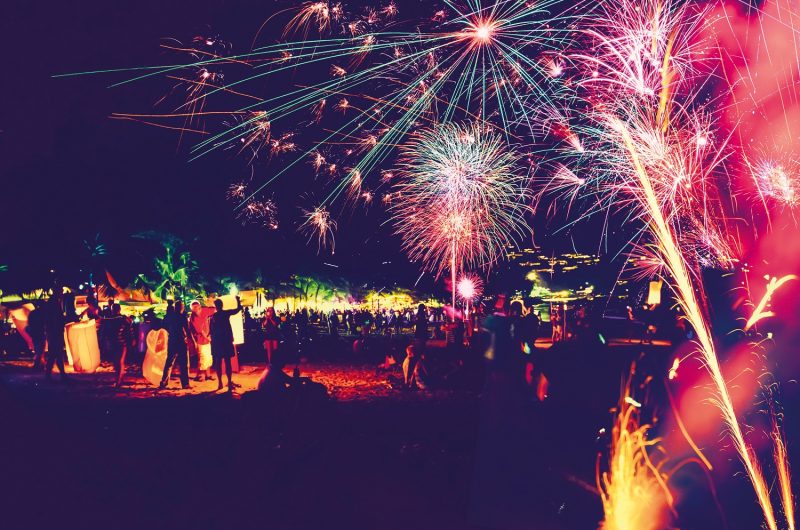 Background festive New Year with fireworks and bokeh. New Year fireworks on the beach.